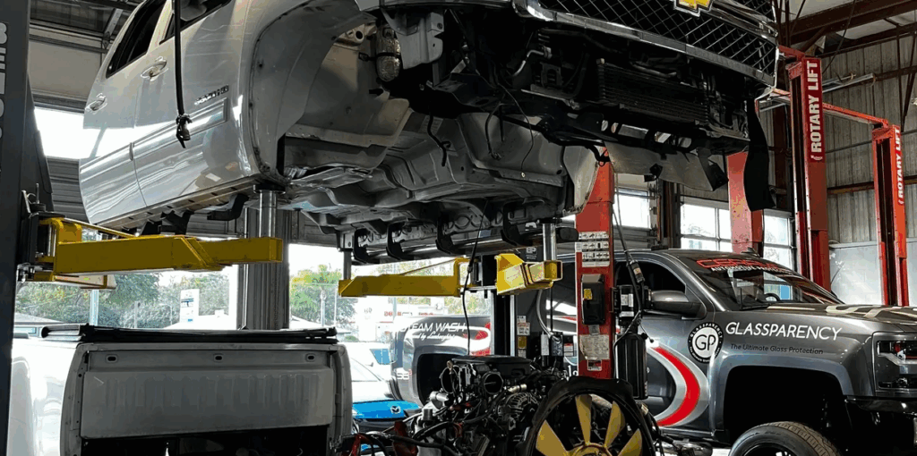 Chevrolet truck lifted on hydraulic car lift for engine repair in auto repair shop