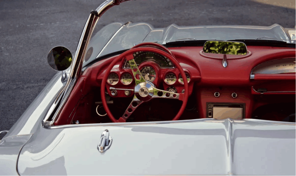 Interior of a classic car with red dashboard and steering wheel