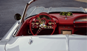 Interior of a classic car with red dashboard and steering wheel